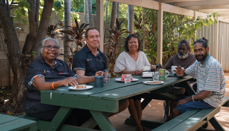 Hostel residents and staff sitting around a table eating