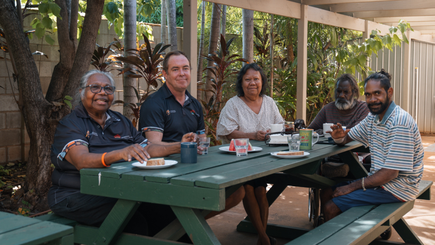 Hostel residents and staff sitting around a table eating