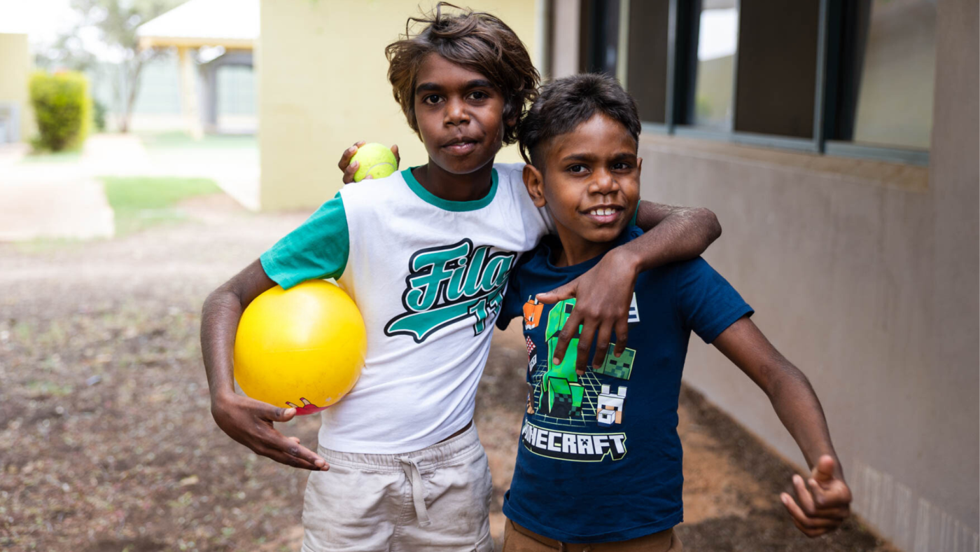 Two hostel residents standing outside the hostel holding a ball